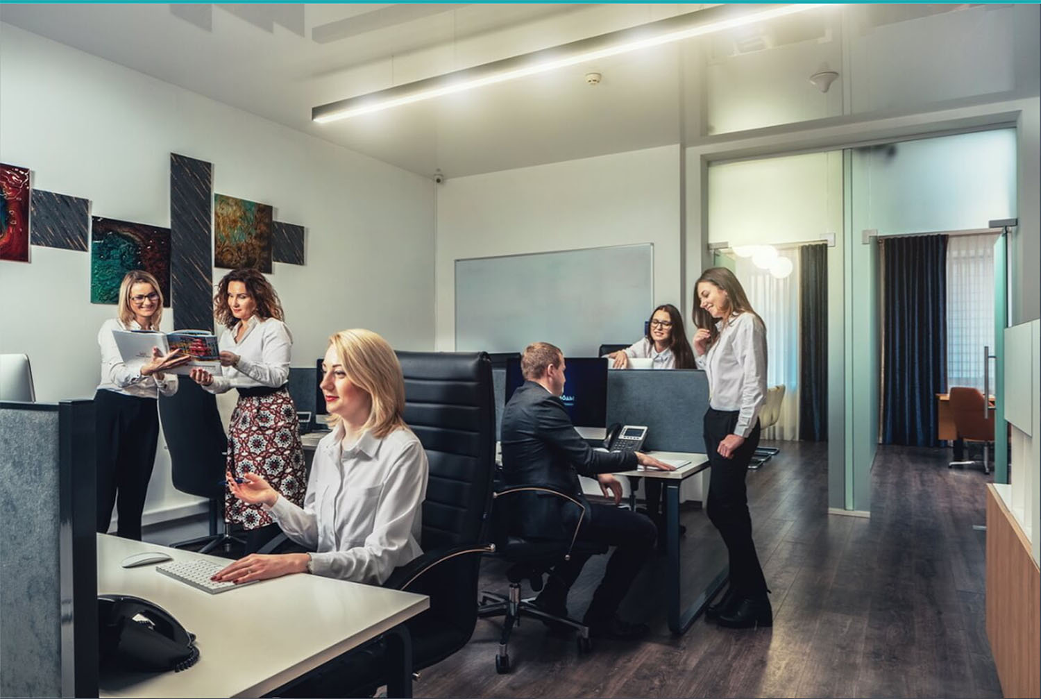 Сотрудники SKYFORM STUDIO работают в открытом офисном пространстве, групповые обсуждения за рабочими столами, современный интерьер с произведениями искусства на стенах.