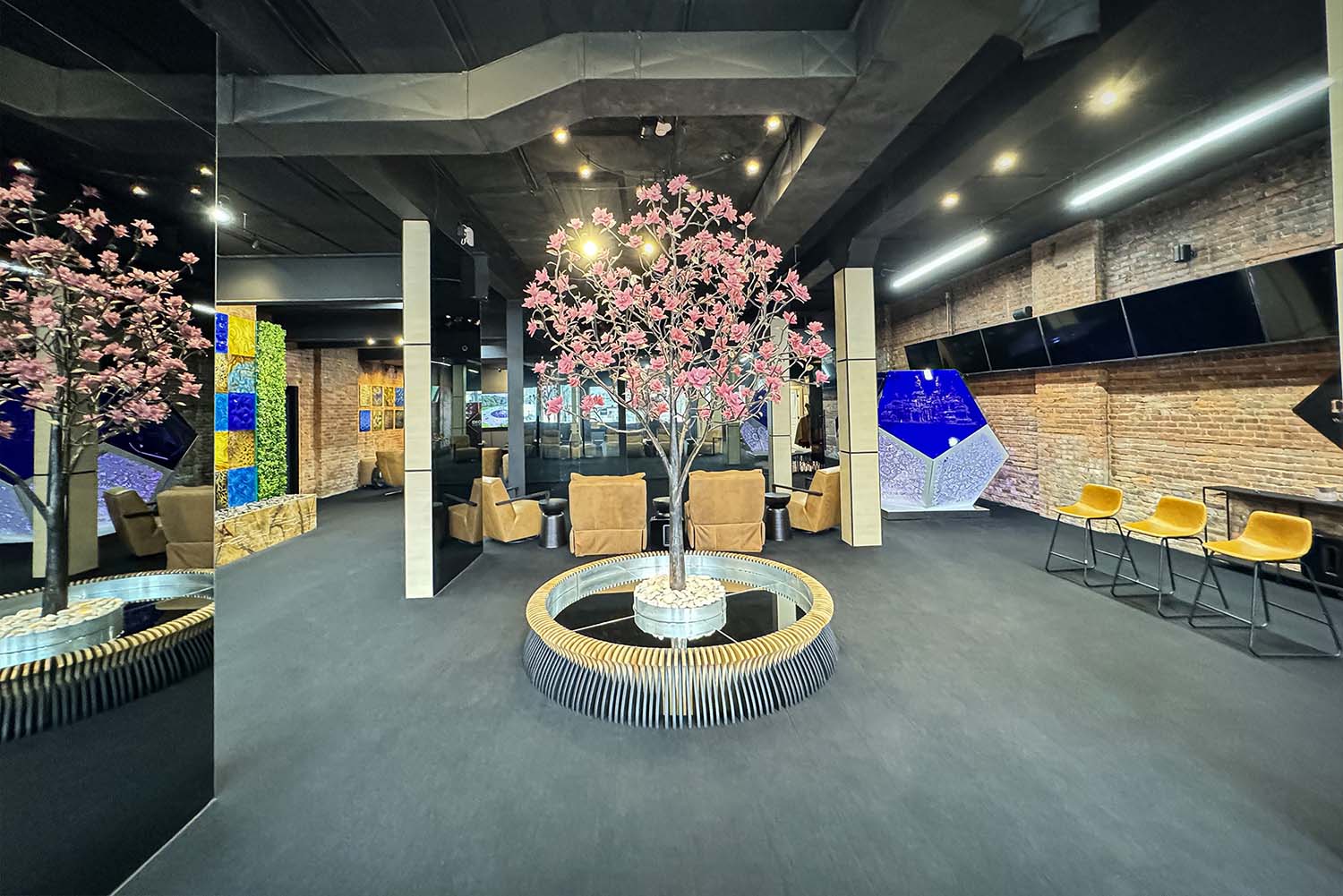 SKYFORM studio көрмесінің орталық сәндік ағаш орнатылуы, демалыс бөлмесі, жасыл желектер мен панельдері бар көркем қабырғалары бар.