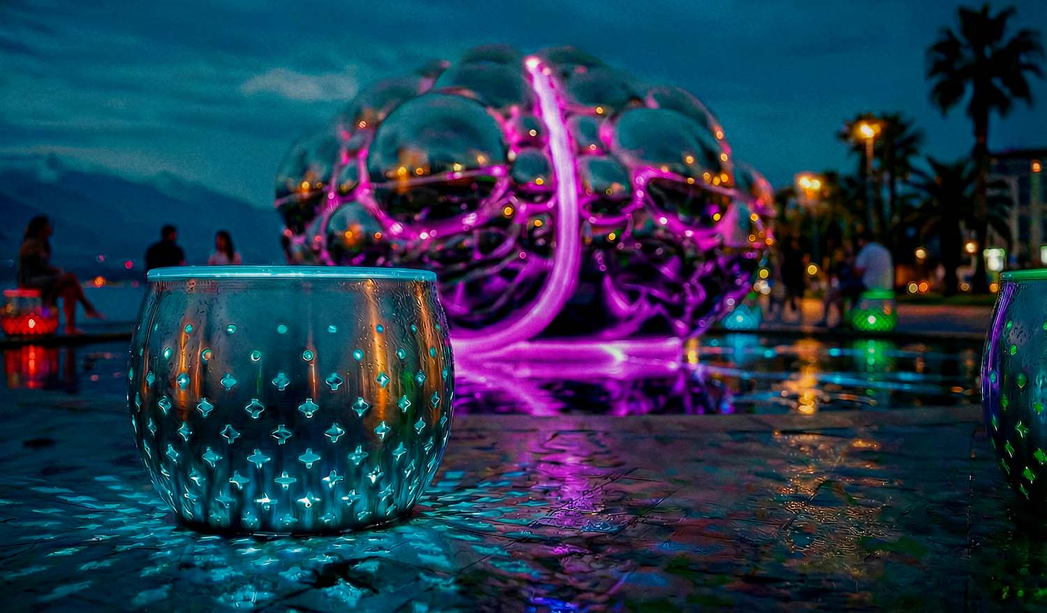 Светящаяся металлическая тумба с художественной перфорацией на переднем плане; на заднем фоне размытая скульптура мозга с яркой розовой подсветкой.