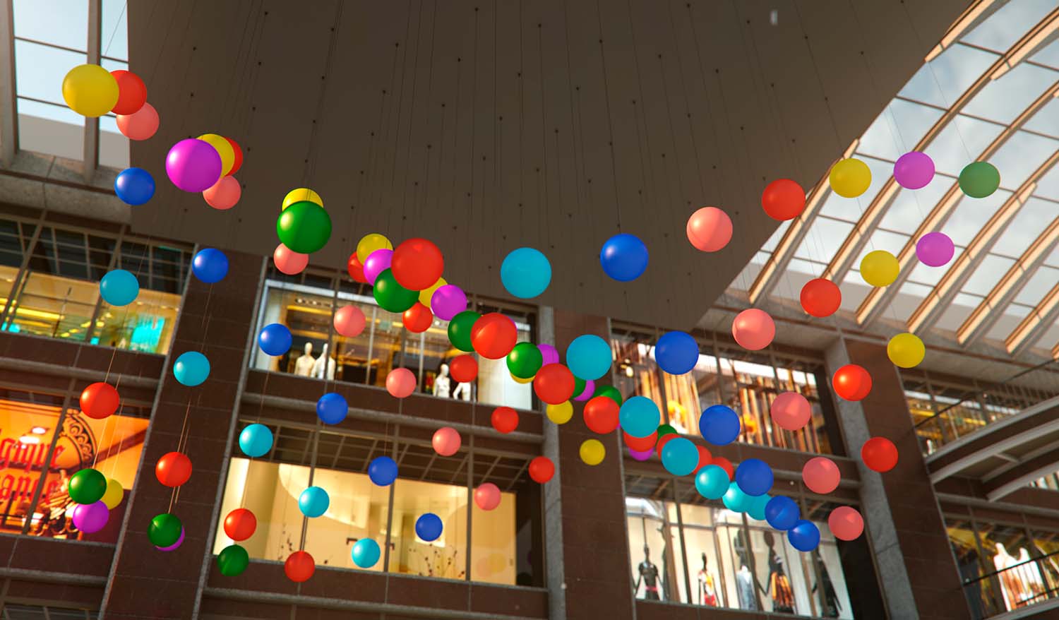 Кинетическая инсталляция в атриуме торгового центра — десятки подвешенных разноцветных сфер формируют динамичную волнообразную композицию под стеклянной крышей, создавая ощущение движения и праздничной атмосферы.