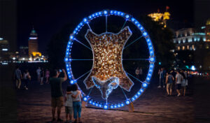 Public art installation “Golden Fleece” in the form of a ram with a golden frame, illuminated by RGB lighting.