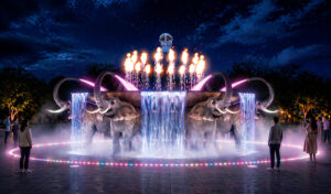 An illuminated public art installation featuring an elephant-shaped fountain at night.